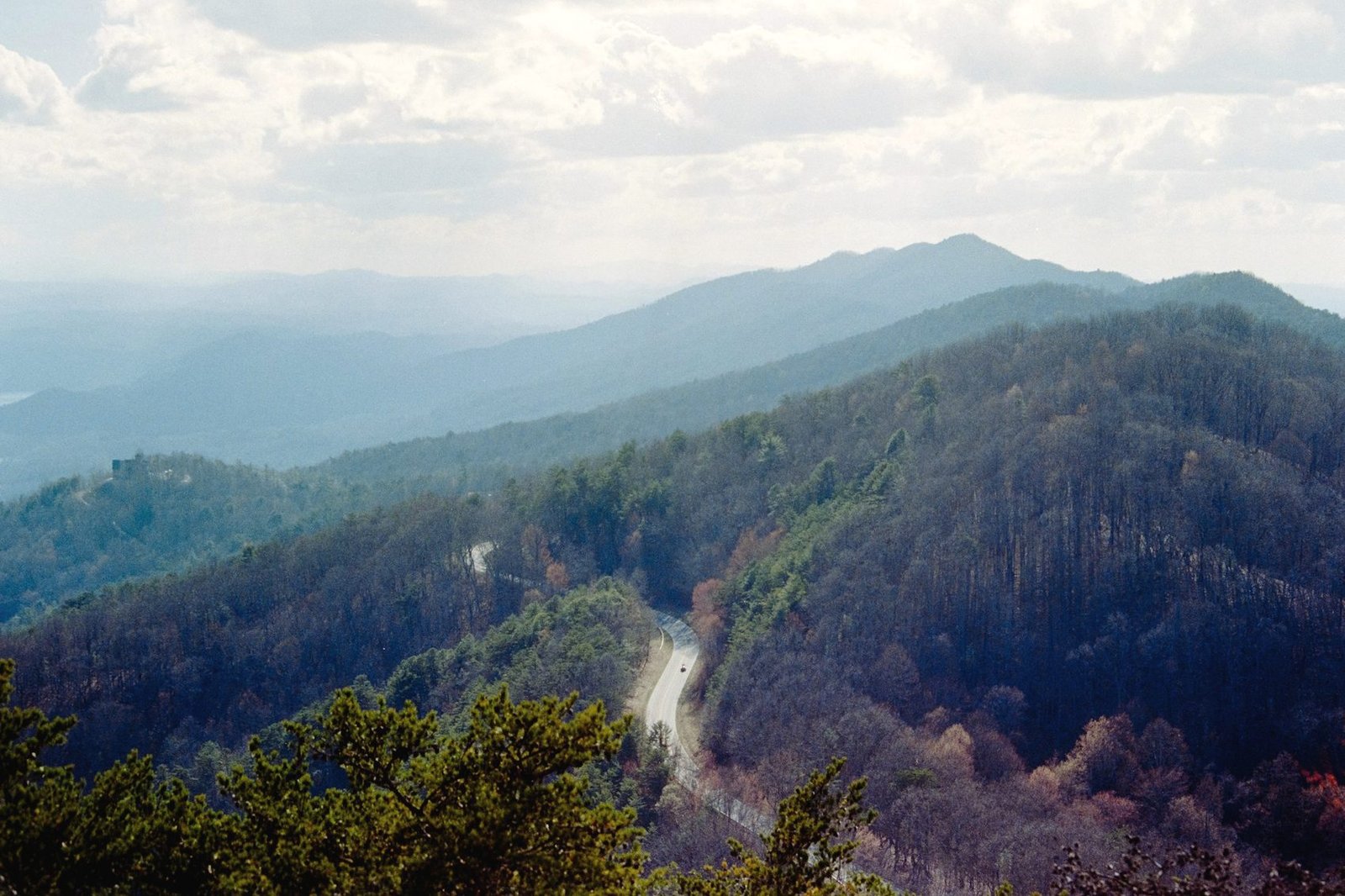 Forested blue ridges fading into haze, with a road threading through the valley below