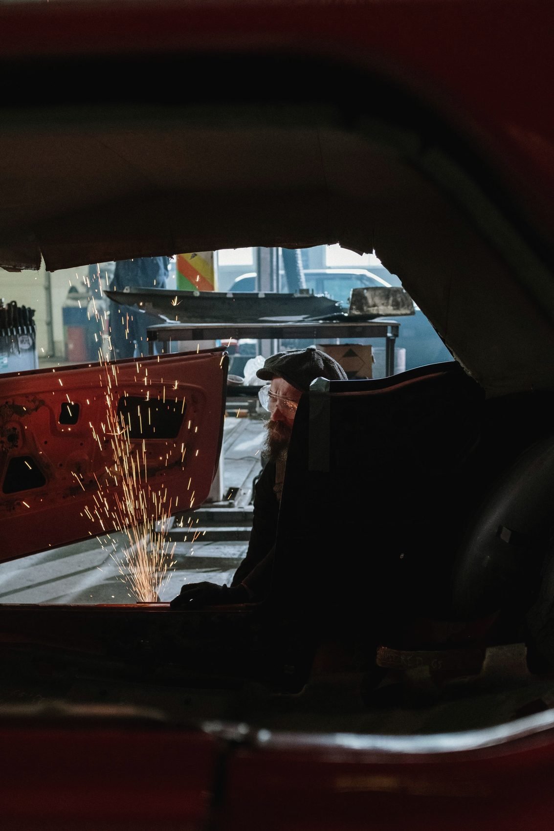 Grinding sparks seen through the window opening of a red car body
